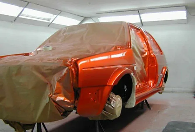 Spray gun applying paint to a vehicle panel
